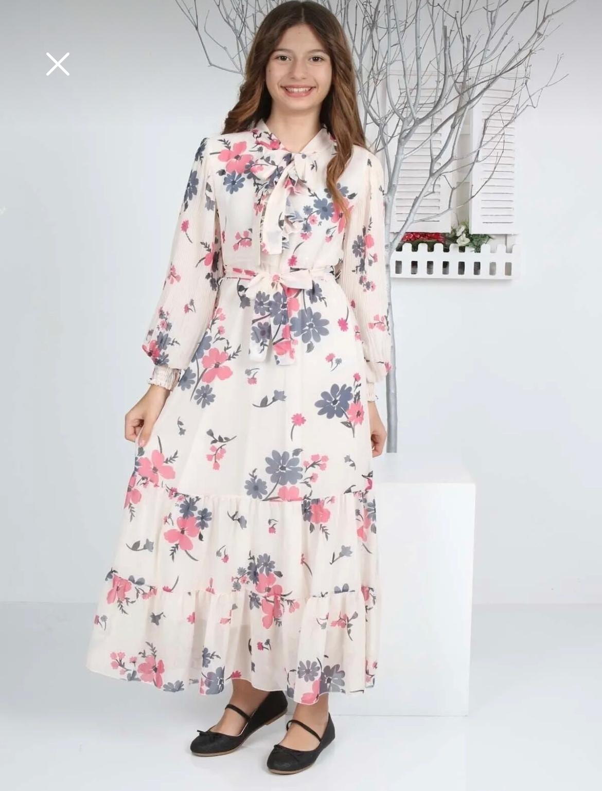 Woman wearing a floral dress standing against a white background
