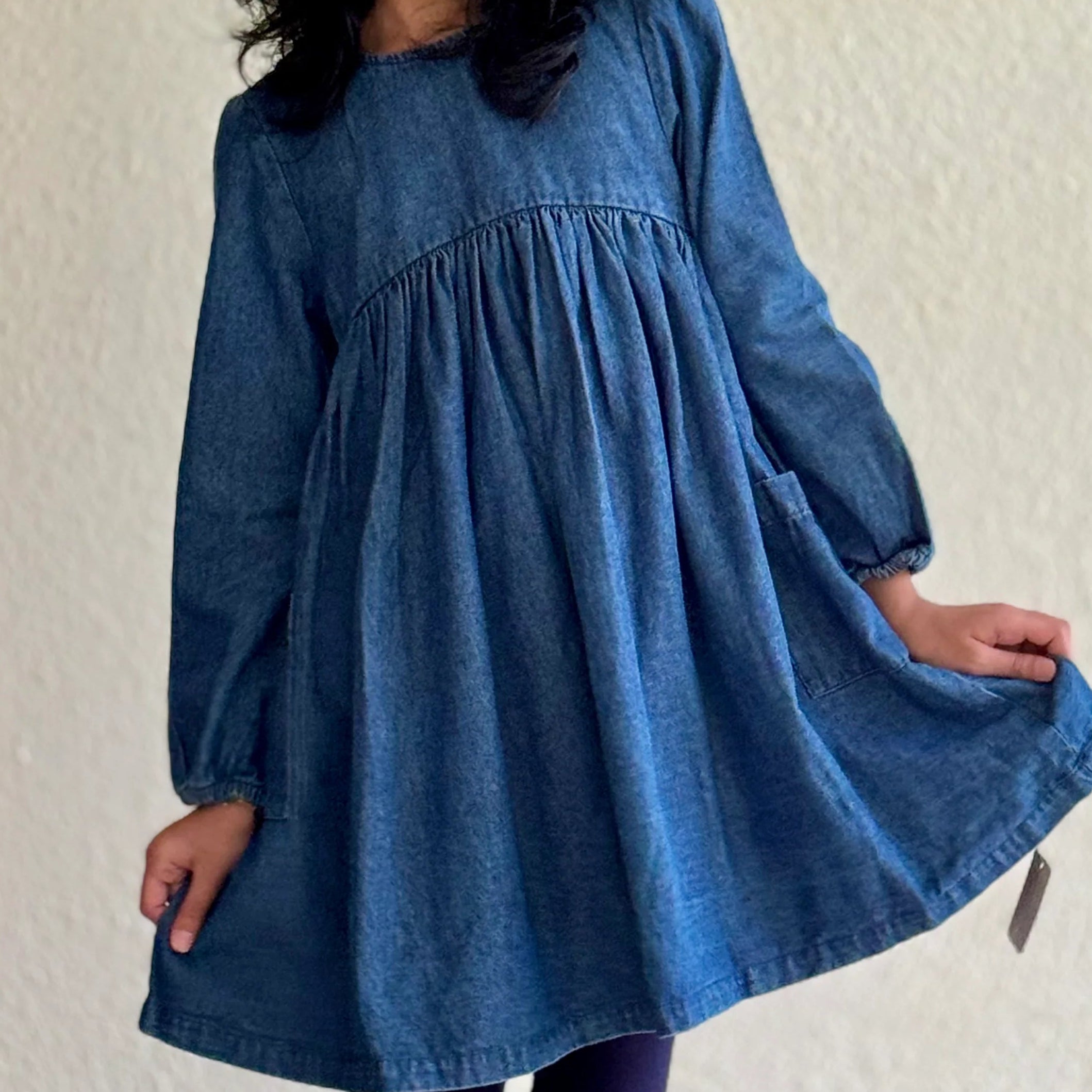 Young girl wearing a blue dress against a plain background