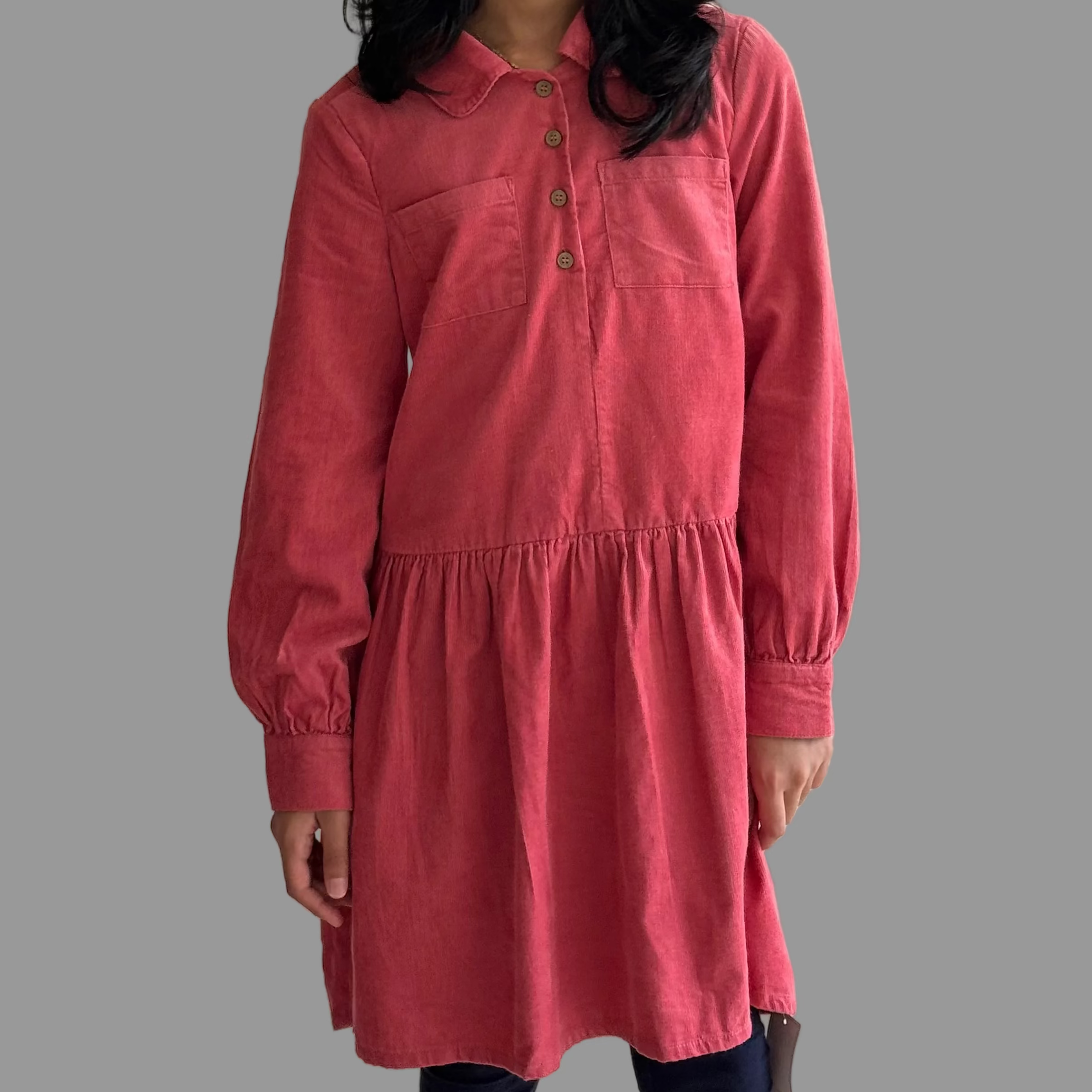 Young girl wearing a pink dress against a plain wall