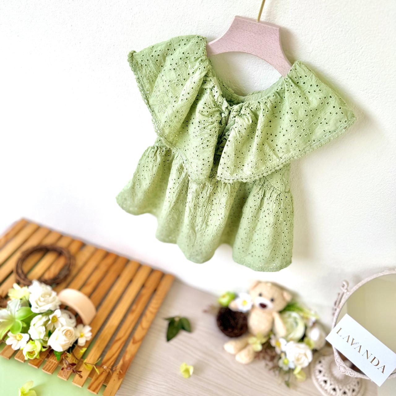 Light green baby dress with ruffled details on a white background
