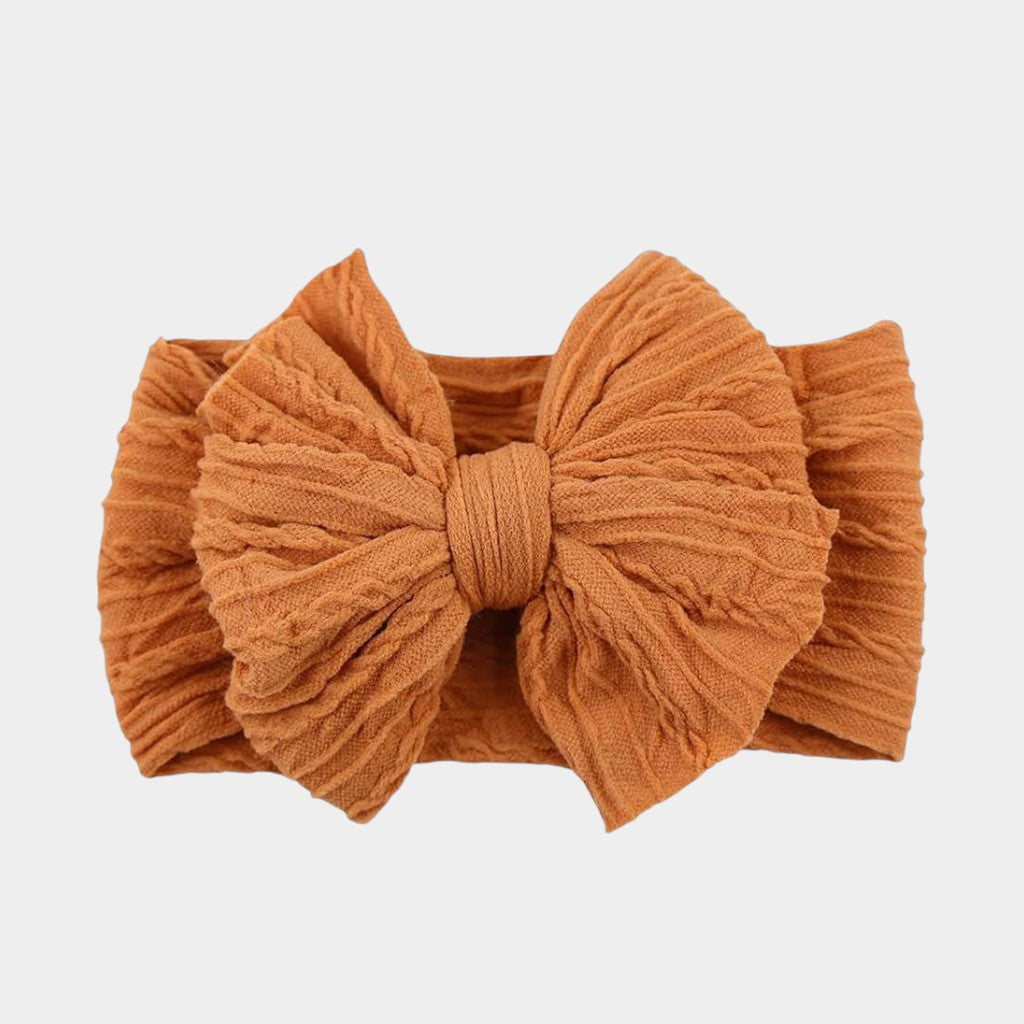 Orange headband with a large bow on a light gray background